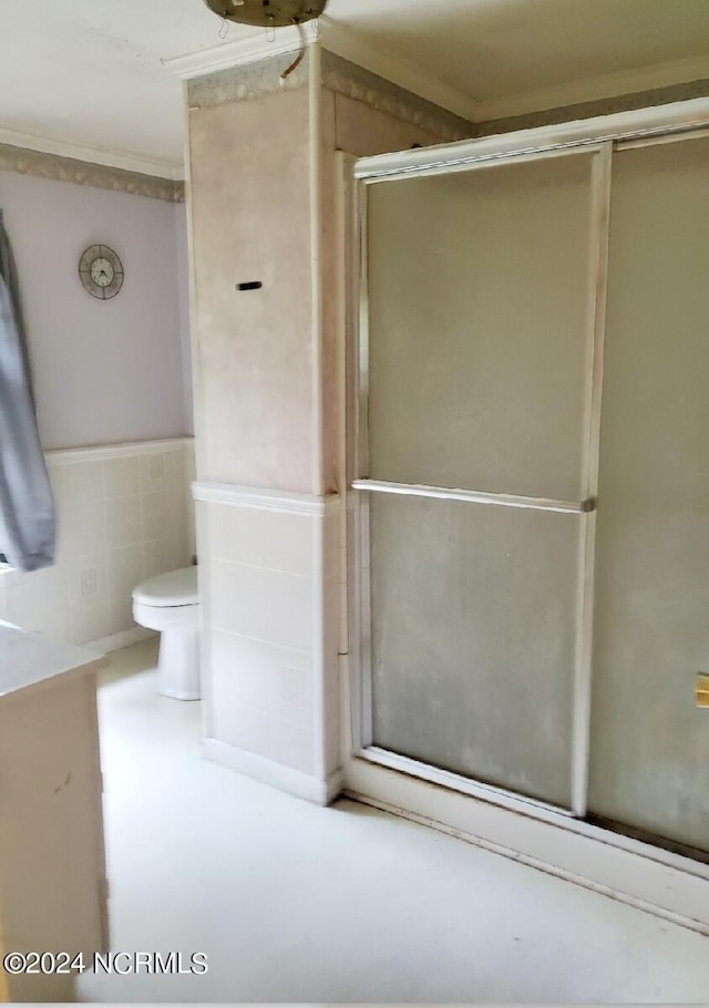 bathroom with an enclosed shower, toilet, tile walls, and crown molding