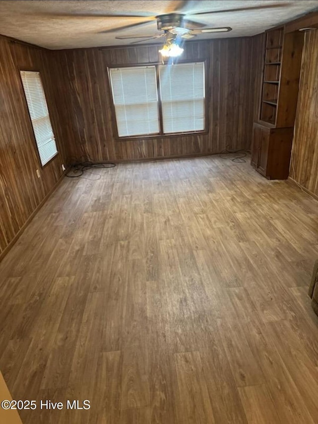 714 Walnut St, Laurinburg, NC 28352 - unfurnished room featuring a ceiling fan, wooden walls, and light wood-style floors