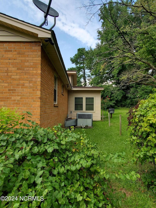 view of side of property featuring central AC unit and a lawn