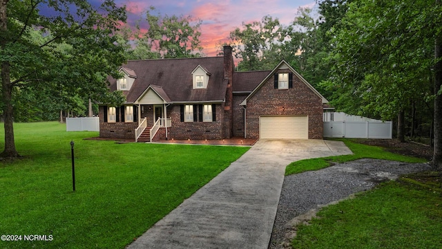 cape cod home featuring a garage and a lawn