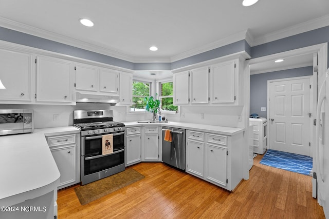 kitchen with appliances with stainless steel finishes, white cabinetry, sink, ornamental molding, and light hardwood / wood-style flooring