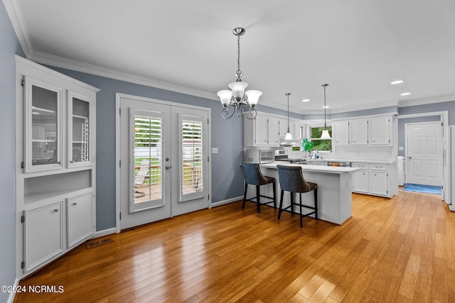 kitchen with stainless steel stove, a breakfast bar area, white cabinets, and kitchen peninsula