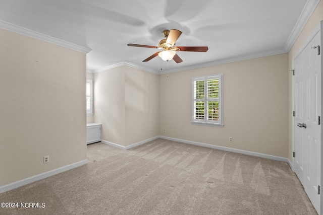 carpeted spare room featuring crown molding and ceiling fan