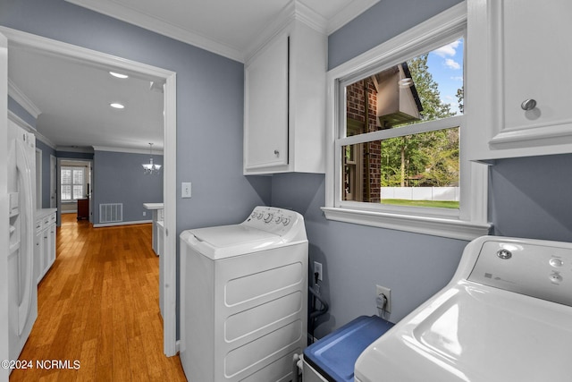 laundry area with crown molding, cabinets, separate washer and dryer, and light hardwood / wood-style floors