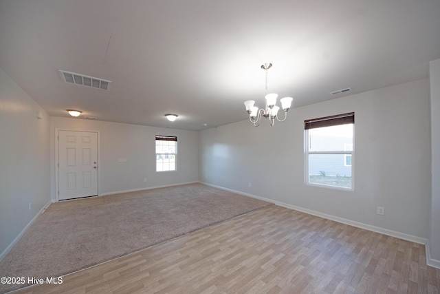 unfurnished room featuring light carpet and a chandelier