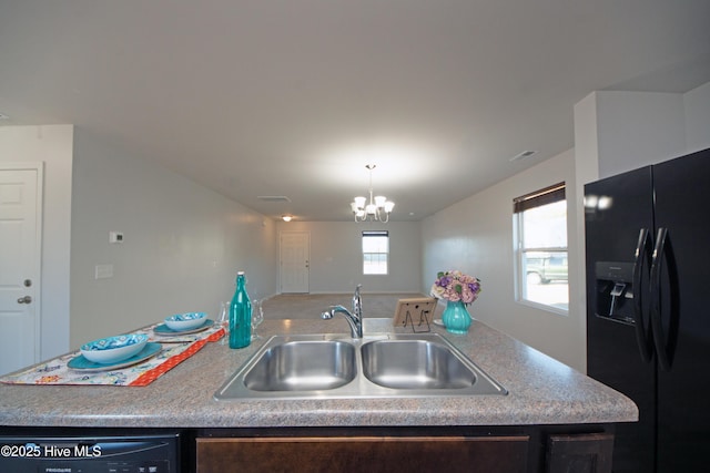 kitchen featuring black appliances, a center island with sink, sink, a notable chandelier, and dark brown cabinetry