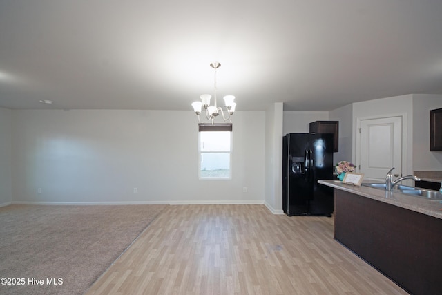 kitchen with dark brown cabinetry, sink, black fridge, a chandelier, and pendant lighting