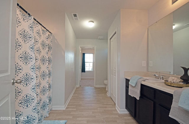 bathroom with wood-type flooring, vanity, and toilet