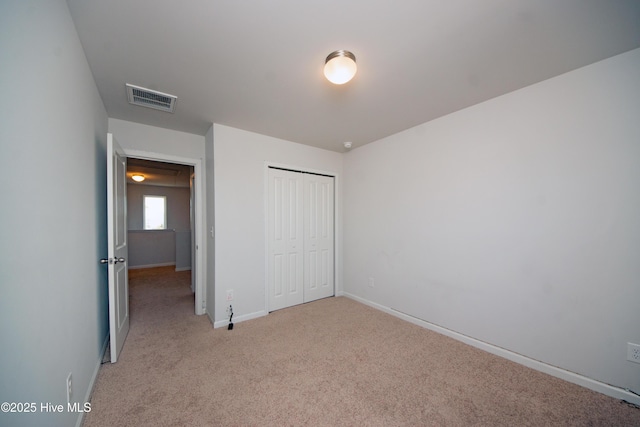 unfurnished bedroom with light carpet and a closet