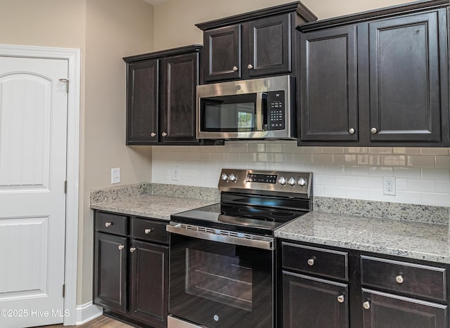 kitchen featuring appliances with stainless steel finishes, tasteful backsplash, and light stone countertops