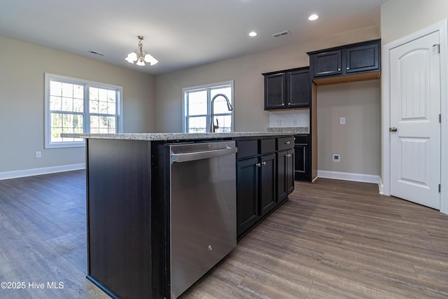 kitchen with stainless steel dishwasher, a kitchen island with sink, dark hardwood / wood-style floors, and hanging light fixtures