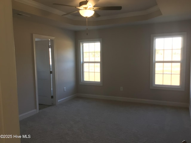 spare room featuring ceiling fan, a tray ceiling, and dark carpet