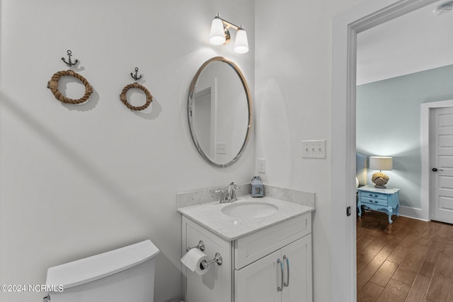 bathroom featuring vanity, wood finished floors, toilet, and baseboards