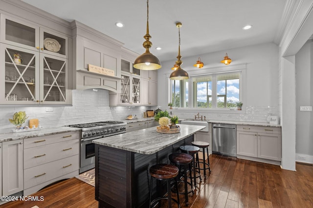 kitchen featuring pendant lighting, tasteful backsplash, stainless steel appliances, a kitchen island, and dark hardwood / wood-style floors