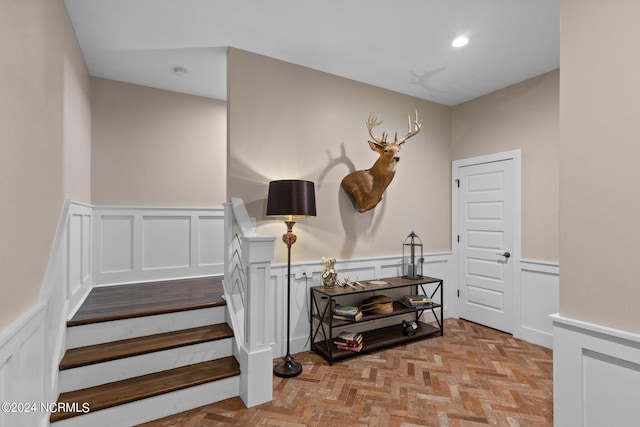 staircase with a wainscoted wall, recessed lighting, and a decorative wall