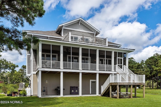 rear view of house featuring a balcony, a yard, and a sunroom