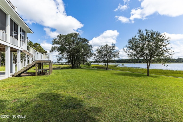 view of yard with stairway, a water view, and a sunroom