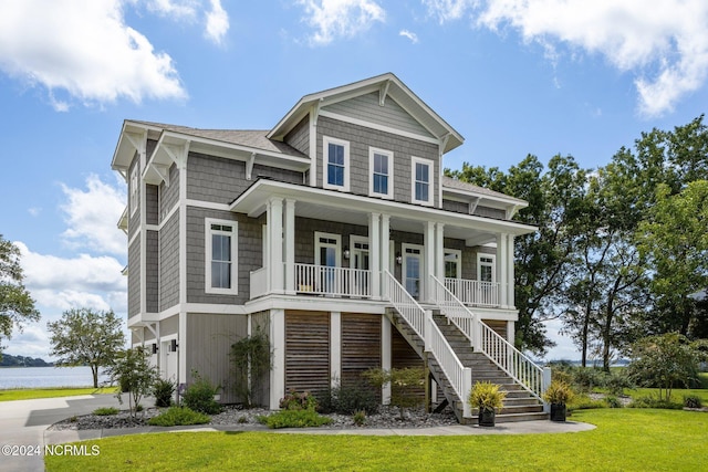 raised beach house with driveway, a garage, stairway, covered porch, and a front lawn