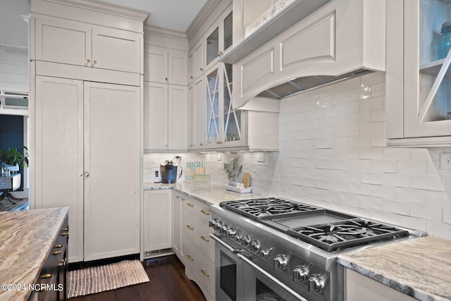 kitchen with white cabinetry, double oven range, decorative backsplash, light stone countertops, and custom range hood