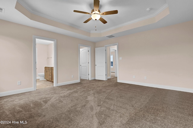 unfurnished bedroom featuring ornamental molding, light carpet, a tray ceiling, ceiling fan, and ensuite bathroom