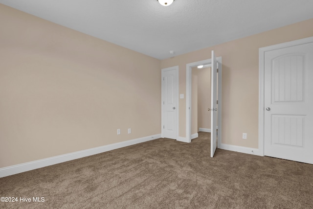 unfurnished bedroom with a textured ceiling and carpet floors