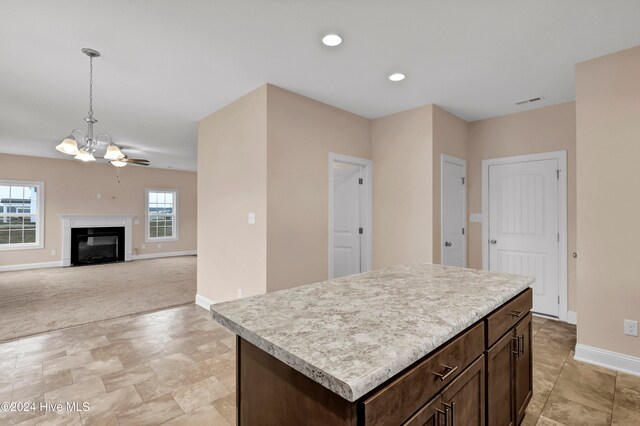 kitchen featuring light carpet, ceiling fan, dark brown cabinets, a center island, and pendant lighting