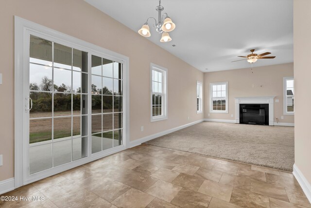 unfurnished living room featuring ceiling fan with notable chandelier and light carpet