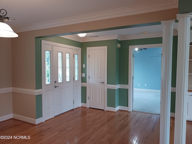 entryway featuring ornamental molding, hardwood / wood-style flooring, and decorative columns