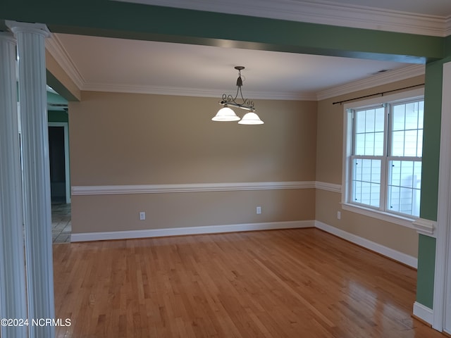 spare room featuring crown molding, hardwood / wood-style floors, and ornate columns