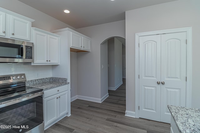 kitchen featuring appliances with stainless steel finishes, tasteful backsplash, light stone countertops, and white cabinets