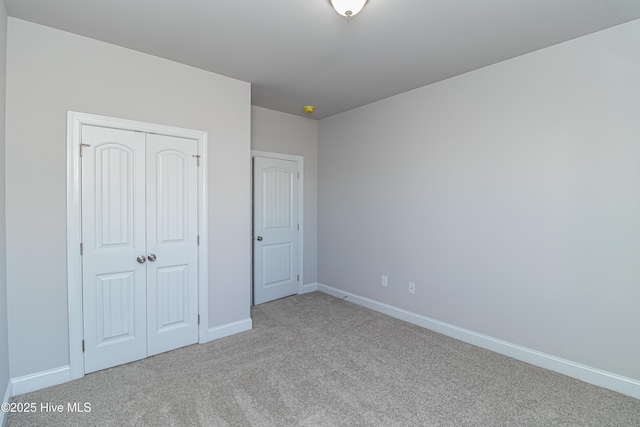 unfurnished bedroom featuring a closet and light colored carpet