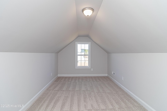 additional living space with vaulted ceiling and light carpet