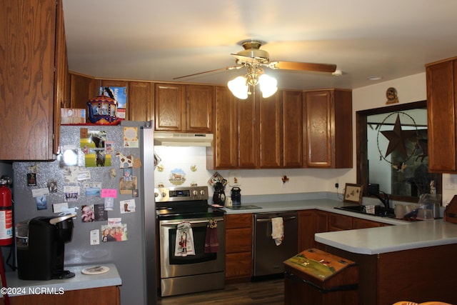 kitchen with light countertops, appliances with stainless steel finishes, a sink, a peninsula, and under cabinet range hood