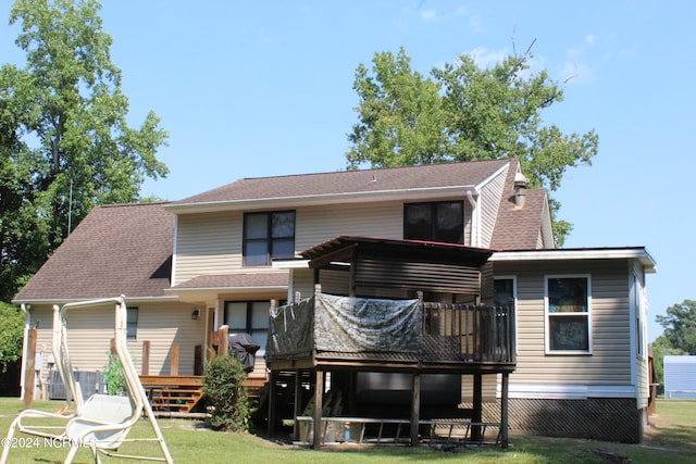 back of house featuring a shingled roof, a lawn, and a wooden deck