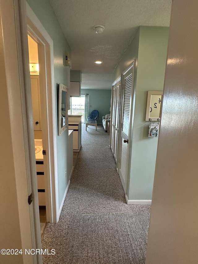 hallway featuring light carpet and baseboards