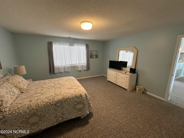 bedroom featuring dark carpet, a textured ceiling, and baseboards