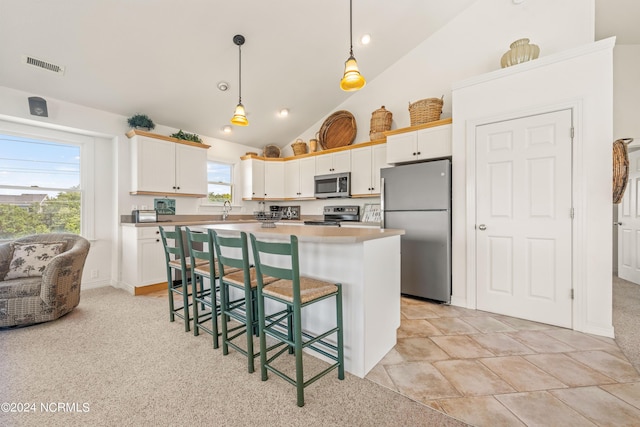 kitchen with stainless steel appliances, a breakfast bar, visible vents, hanging light fixtures, and a center island