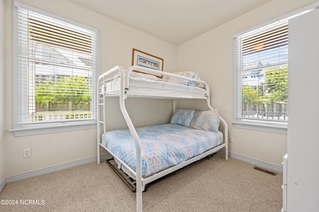 carpeted bedroom featuring visible vents, baseboards, and multiple windows