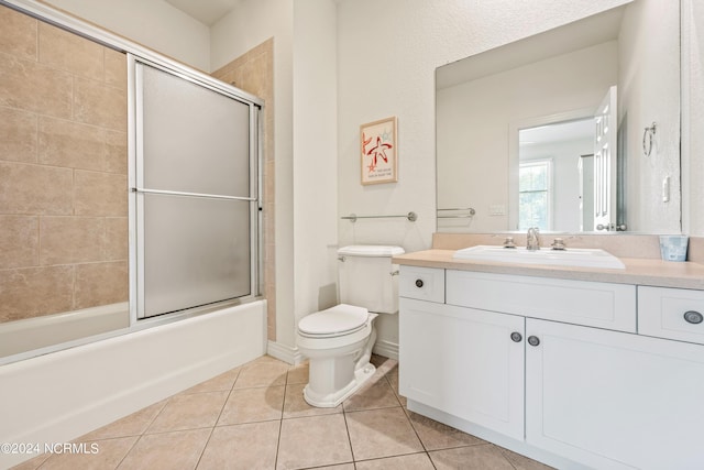 full bath featuring bath / shower combo with glass door, baseboards, toilet, tile patterned flooring, and vanity