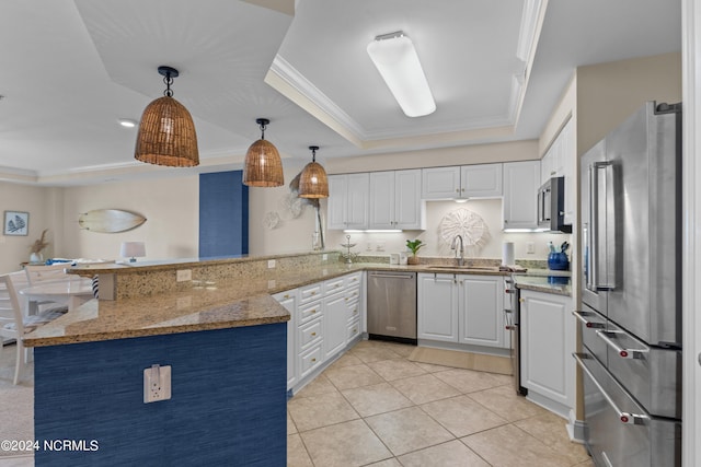 kitchen with white cabinets, appliances with stainless steel finishes, pendant lighting, and kitchen peninsula