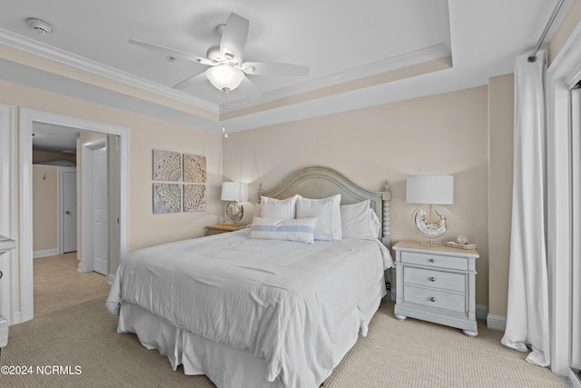 bedroom with light carpet, a tray ceiling, baseboards, and crown molding