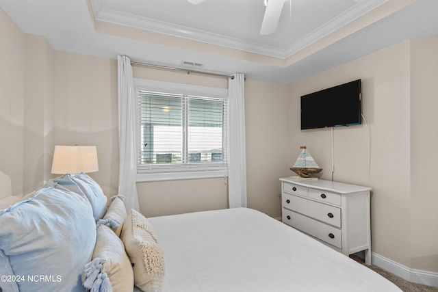 bedroom featuring ornamental molding, a tray ceiling, visible vents, and a ceiling fan