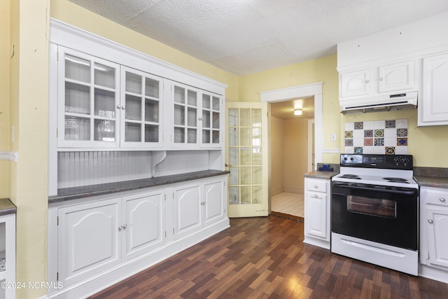 kitchen with dark countertops, glass insert cabinets, white cabinets, range with electric cooktop, and under cabinet range hood