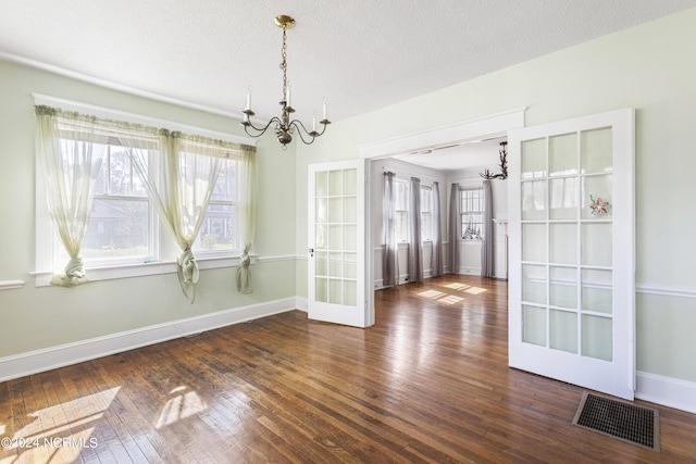 interior space with an inviting chandelier, wood-type flooring, visible vents, and a textured ceiling