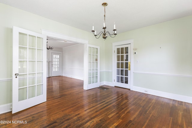 spare room featuring an inviting chandelier, wood-type flooring, baseboards, and french doors