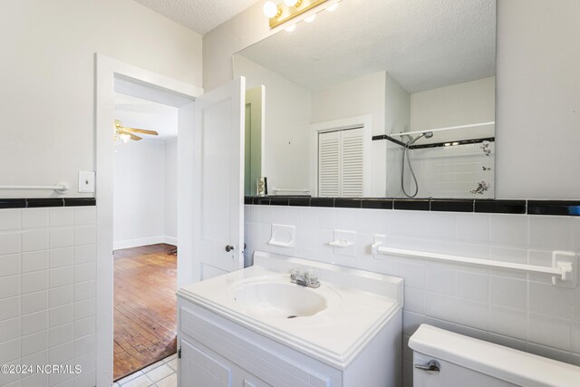 bathroom featuring hardwood / wood-style flooring, toilet, a textured ceiling, and tile walls