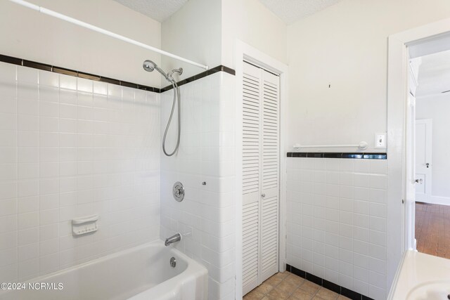 bathroom featuring tiled shower / bath combo, a textured ceiling, and tile patterned floors