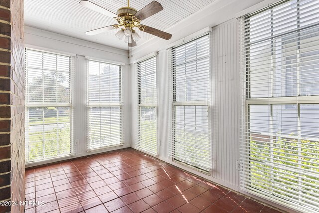 unfurnished sunroom featuring ceiling fan and plenty of natural light