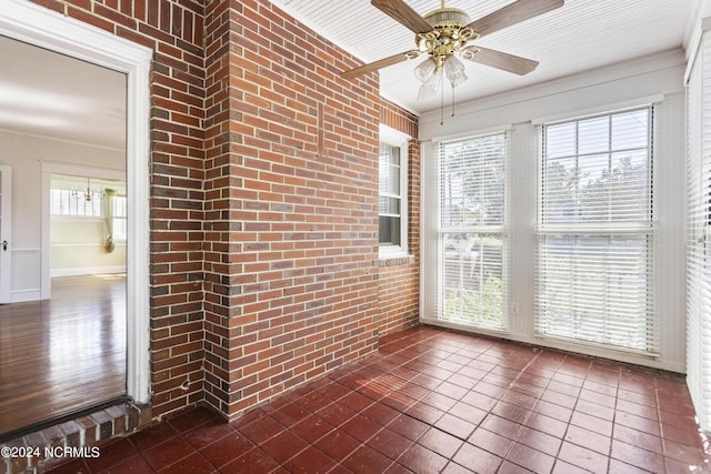 unfurnished sunroom with ceiling fan with notable chandelier and a healthy amount of sunlight