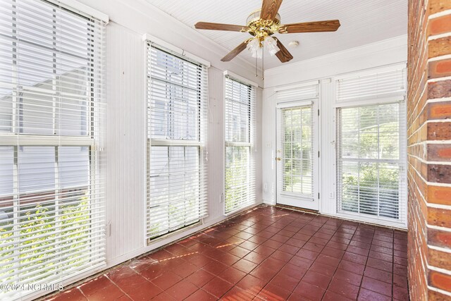 unfurnished sunroom with ceiling fan and a healthy amount of sunlight